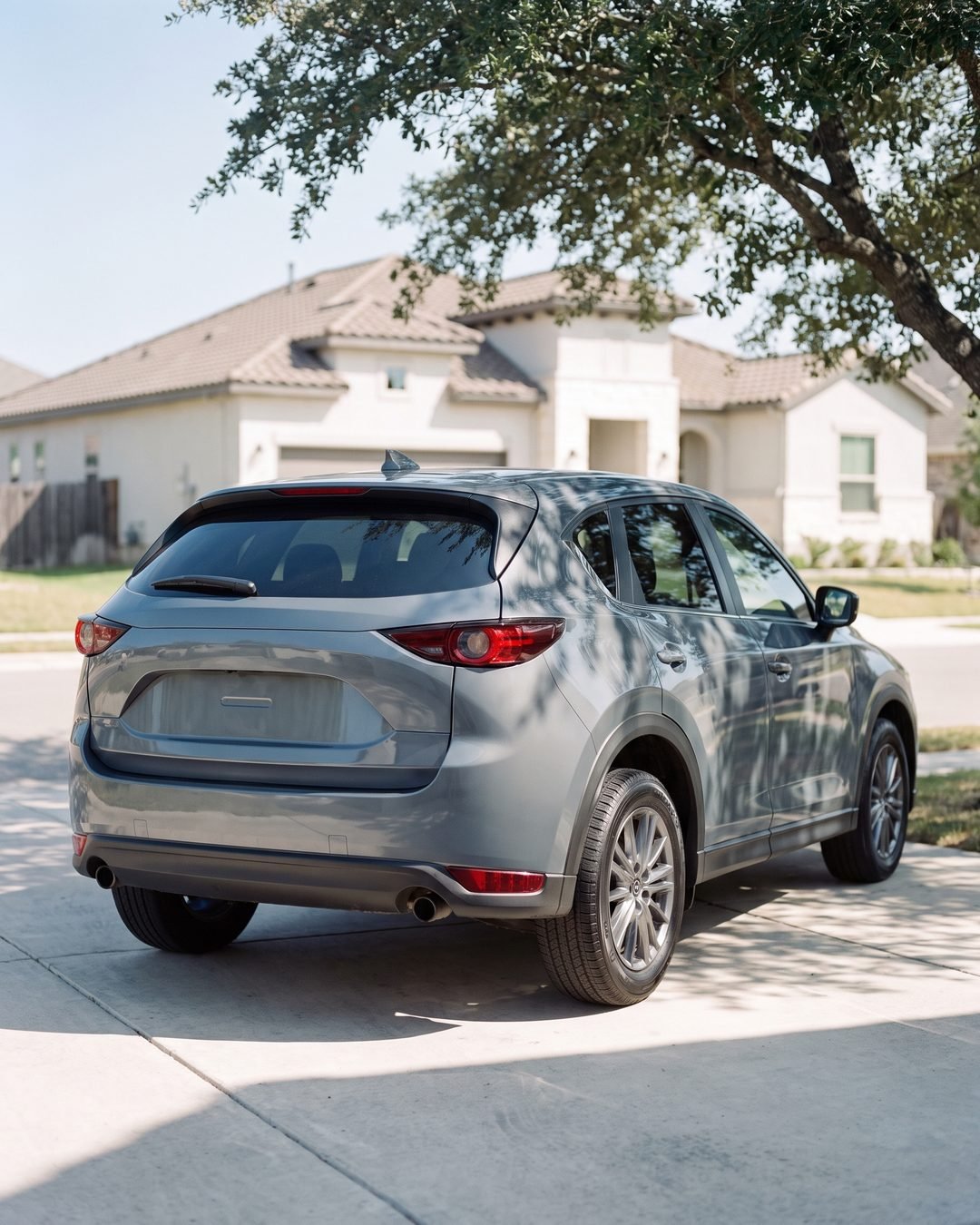 A crossover SUV parked in a suburban San Antonio driveway under a live oak